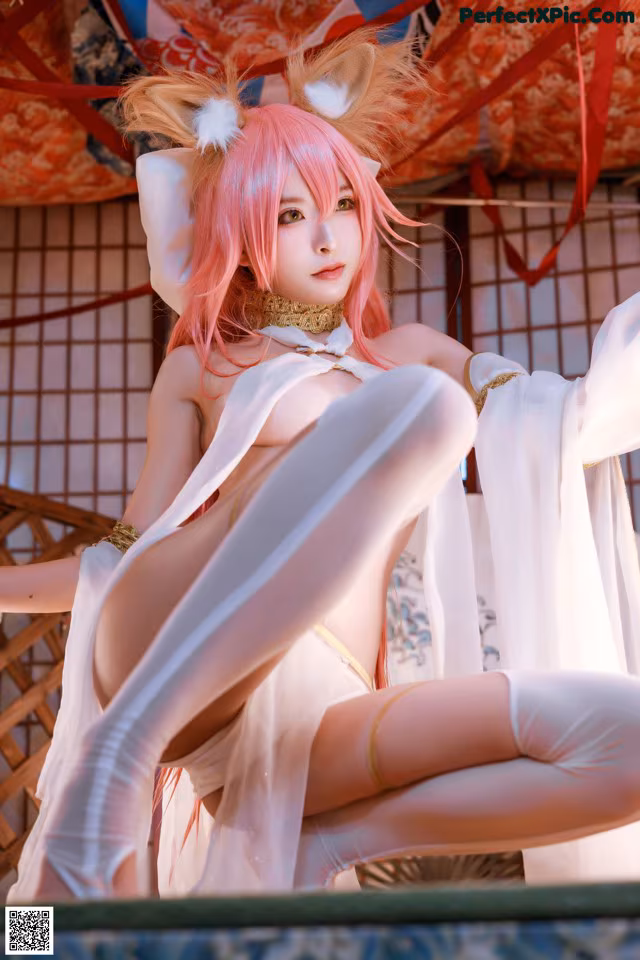 A woman with pink hair sitting on top of a bed.