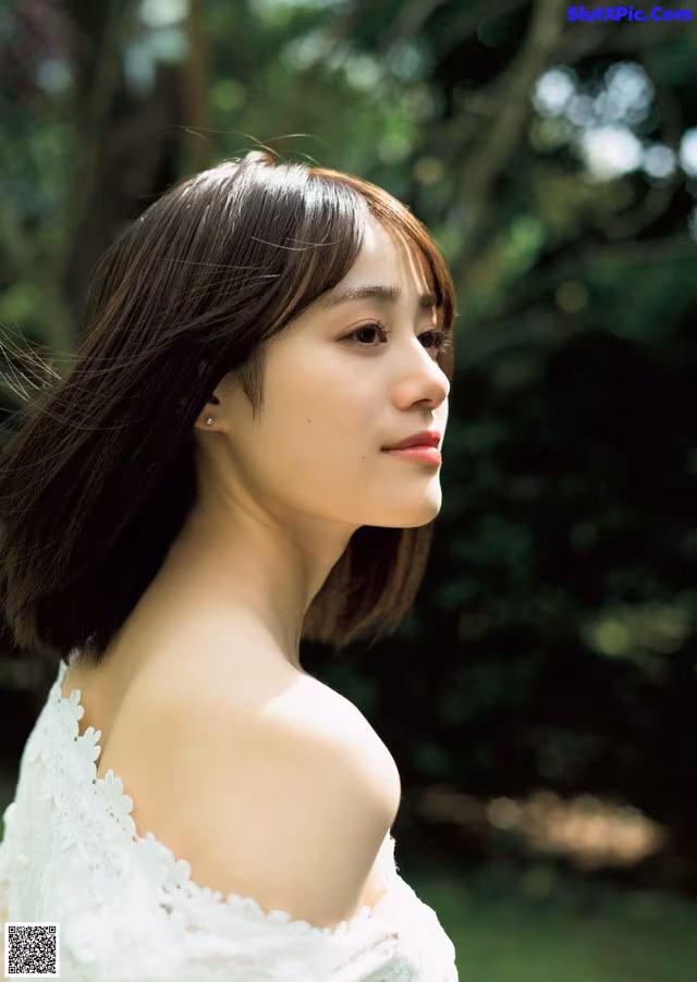 A woman in a white dress standing in the grass.
