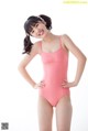 A young girl in a pink swimsuit posing for a picture.