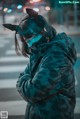 A woman wearing a camouflage jacket and a cat mask.