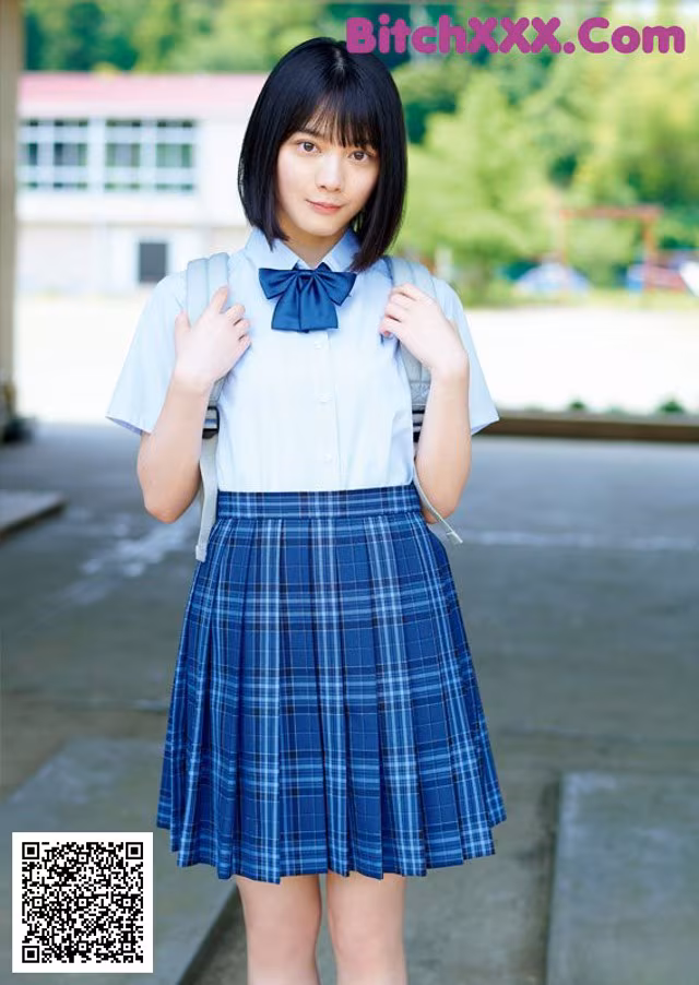 A young woman in a school uniform posing for a picture.