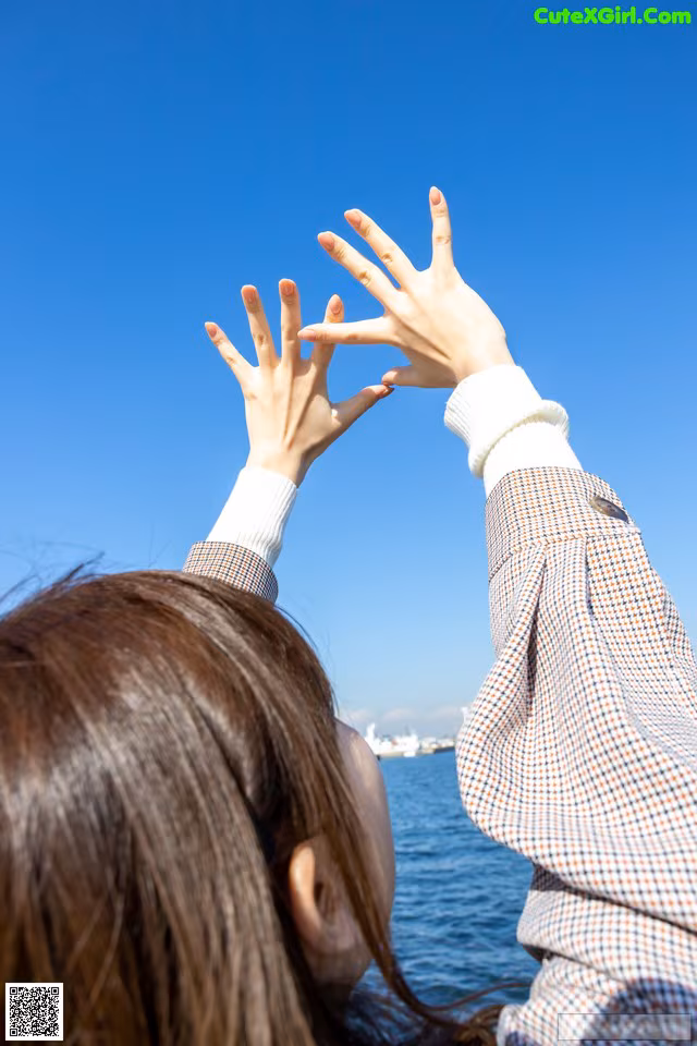 A woman reaching up to the sky with her hands.