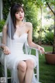 A woman in a wedding dress sitting on a white chair.