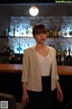 A woman standing in front of a bar in a restaurant.