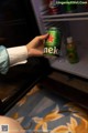 A person holding a can of beer in front of a refrigerator.