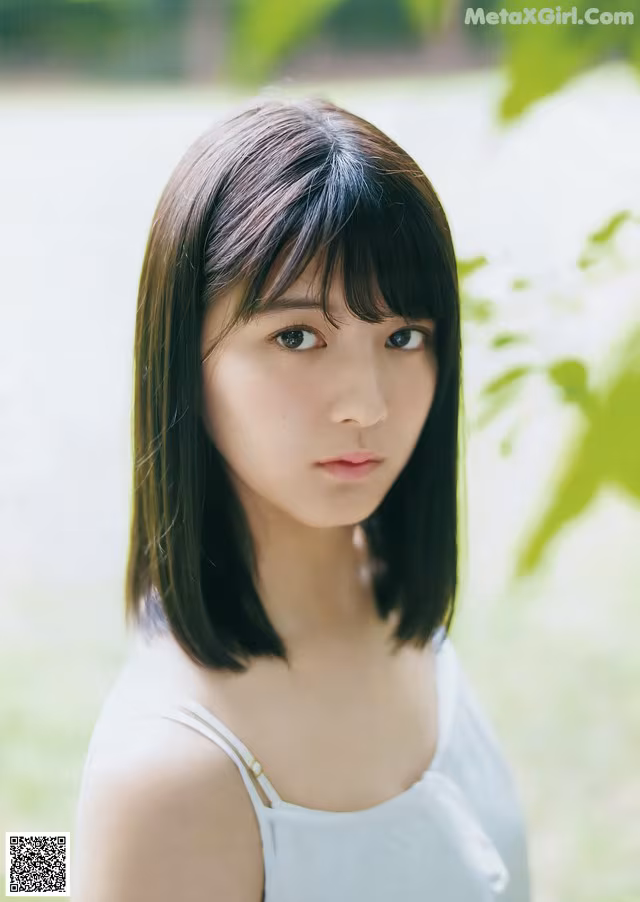 A young woman in a white tank top posing for a picture.