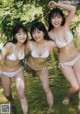 A group of three women in white bikinis standing in the water.