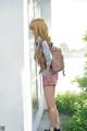 A girl with a backpack standing by a window.