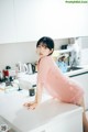 A woman sitting on top of a white counter in a kitchen.