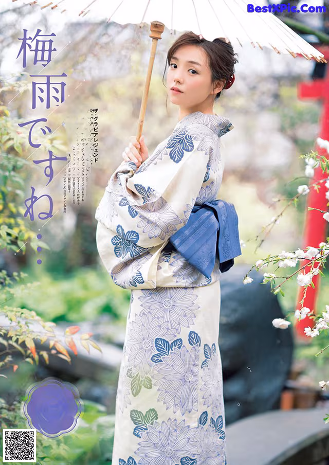 A woman in a kimono holding an umbrella in a garden.