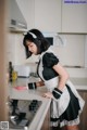 A woman in a maid outfit cleaning a kitchen counter.