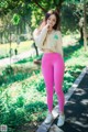 A woman in pink leggings and a white sweatshirt standing on a sidewalk.