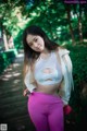 A woman in a white top and pink pants posing for a picture.