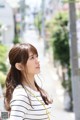 A woman with long brown hair standing on a city street.