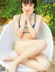 A woman in a blue bikini sitting on a white chair.