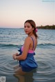 A woman in a blue and pink bathing suit standing in the water.