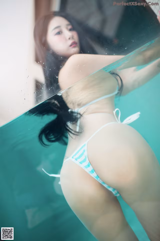 A woman in a blue and white bikini standing in a pool.