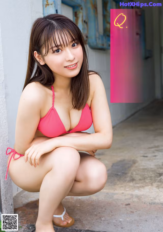 A woman in a pink bikini sitting on the ground.