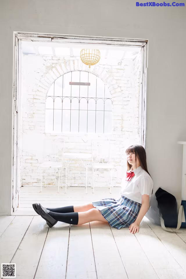 A woman sitting on the floor in front of a window.