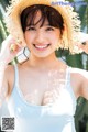 A woman in a straw hat smiles at the camera.