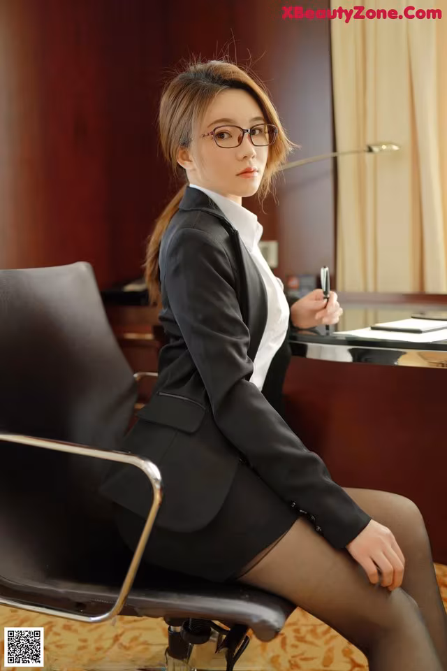 A woman in a business suit sitting at a desk.