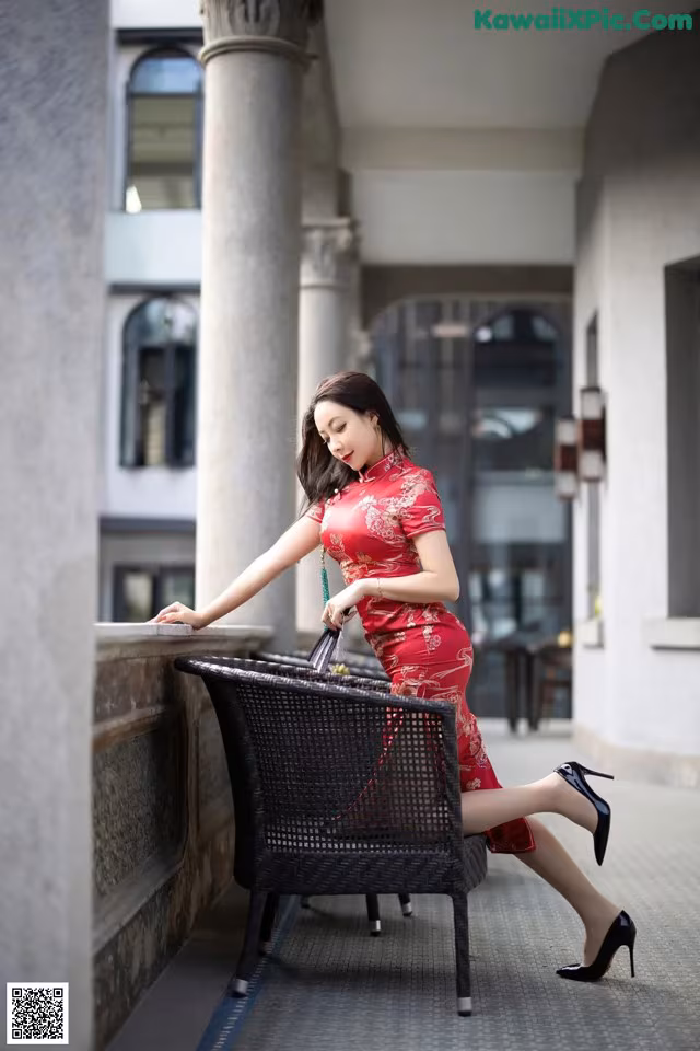 A woman in a red dress sitting on a chair.