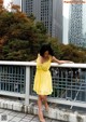 A woman in a yellow dress standing on a bridge.